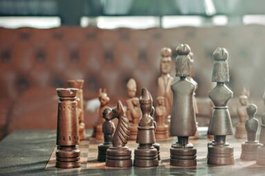 Close-up of a vintage wooden chess set, featuring dark pieces in the foreground with a blurred background, perfect for strategy games.