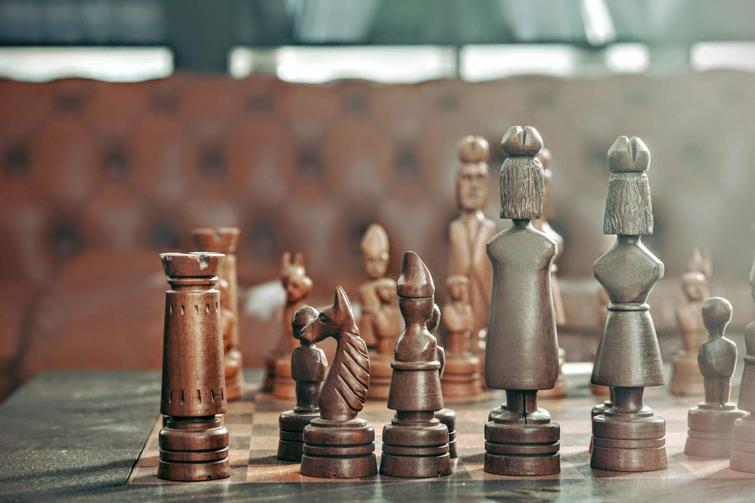 Close-up of a vintage wooden chess set, featuring dark pieces in the foreground with a blurred background, perfect for strategy games.