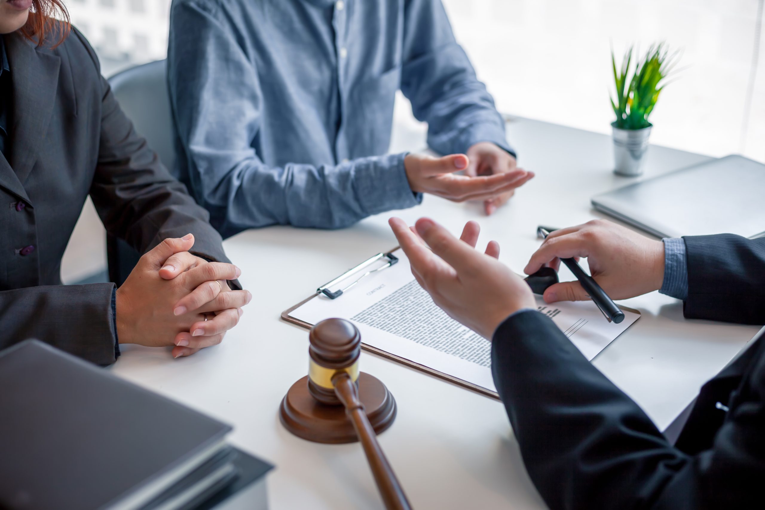 Legal consultation in a modern office, featuring a lawyer advising clients on legal documents, contracts, and justice, with a gavel on the table.